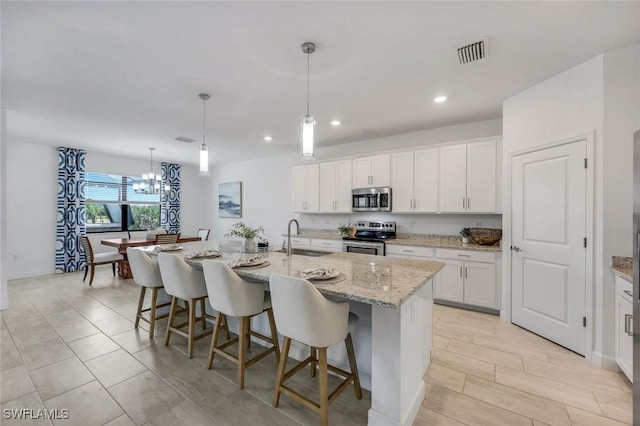 11477 Canopy Loop, Fort Myers, FL 33913 - kitchen featuring appliances with stainless steel finishes, a sink, a kitchen bar, white cabinets, and light stone counters