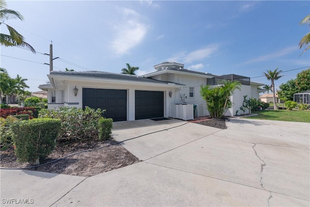 view of front facade with concrete driveway, stucco siding, central AC unit, and a garage