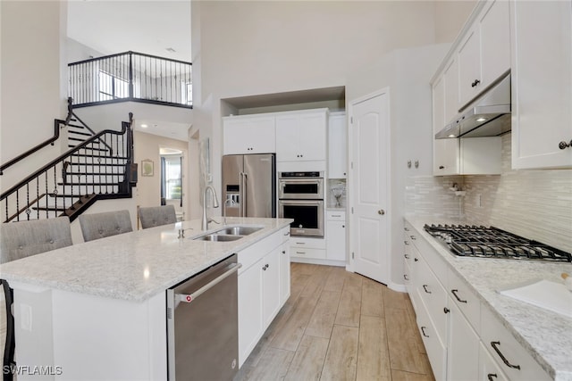 7175 Wilton Dr, Naples, FL 34109 - kitchen with tasteful backsplash, under cabinet range hood, a sink, wood tiled floor, and stainless steel appliances