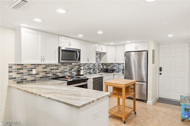 671 E Gulf Dr Unit 2C2, Sanibel, FL 33957 - kitchen featuring a peninsula, white cabinets, light stone counters, a sink, and stainless steel appliances