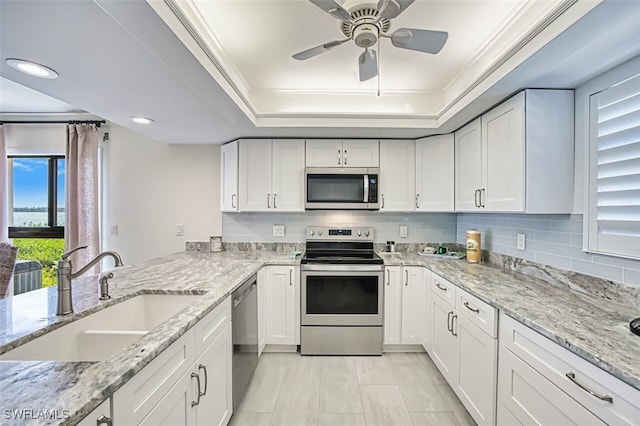15123 Captiva Dr Unit 104, Captiva, FL 33924 - kitchen with ceiling fan, a tray ceiling, appliances with stainless steel finishes, a sink, and decorative backsplash