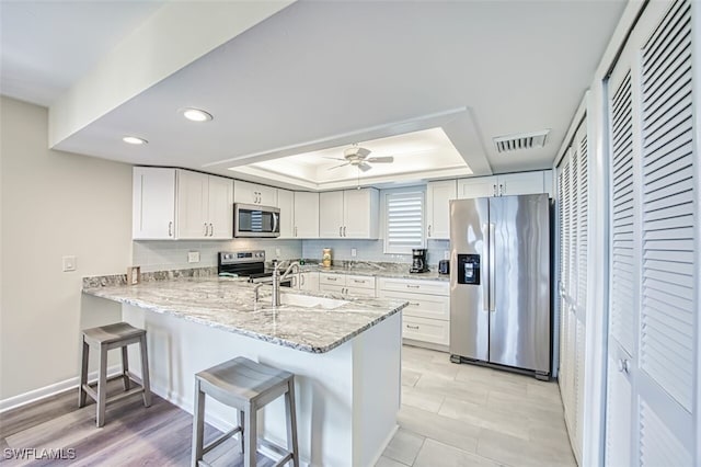 15123 Captiva Dr Unit 104, Captiva, FL 33924 - kitchen with visible vents, a sink, stainless steel appliances, a raised ceiling, and backsplash