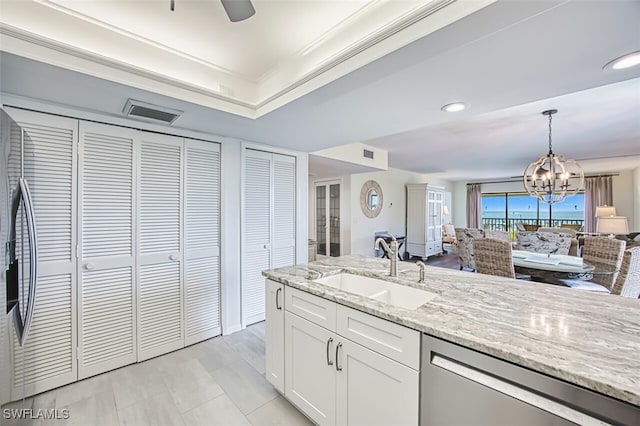 15123 Captiva Dr Unit 104, Captiva, FL 33924 - kitchen featuring stainless steel dishwasher, white cabinets, a sink, open floor plan, and a notable chandelier