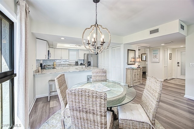 15123 Captiva Dr Unit 104, Captiva, FL 33924 - dining space featuring light wood finished floors, a notable chandelier, baseboards, and visible vents