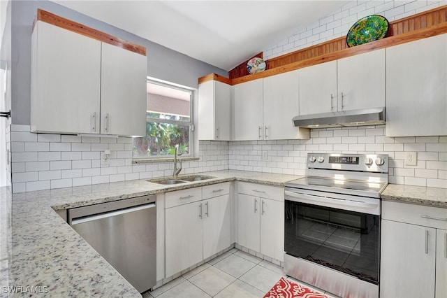 kitchen featuring light tile patterned floors, a sink, appliances with stainless steel finishes, under cabinet range hood, and decorative backsplash