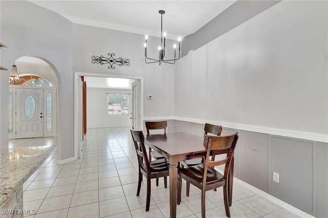 dining space featuring a decorative wall, light tile patterned floors, a notable chandelier, and a wainscoted wall