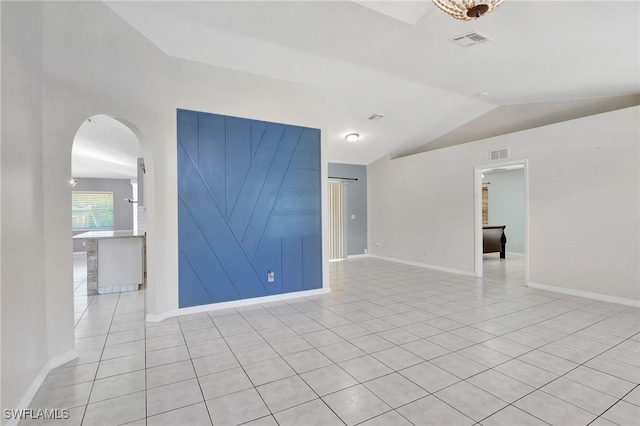 spare room with arched walkways, light tile patterned floors, visible vents, and lofted ceiling