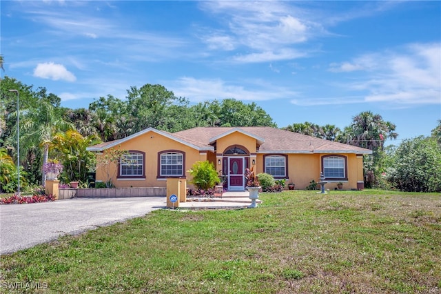 single story home with driveway, stucco siding, and a front lawn
