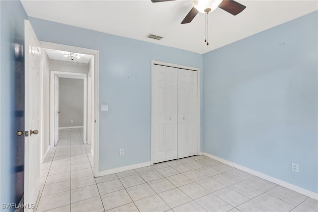 unfurnished bedroom featuring a closet, baseboards, light tile patterned floors, a ceiling fan, and visible vents
