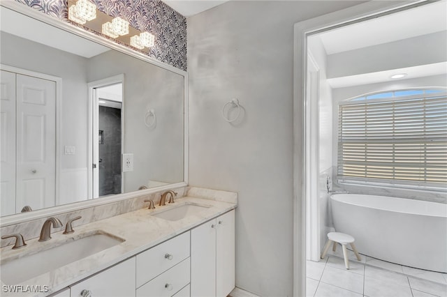 bathroom with tile patterned floors, a freestanding tub, double vanity, and a sink