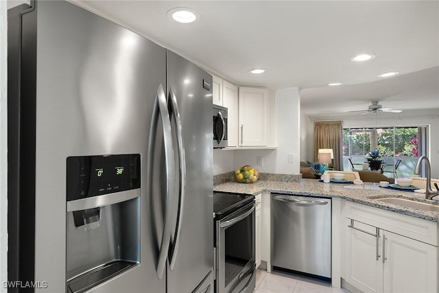 kitchen featuring a ceiling fan, white cabinetry, light stone counters, a sink, and stainless steel appliances