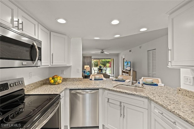 kitchen with a sink, white cabinets, appliances with stainless steel finishes, and a peninsula