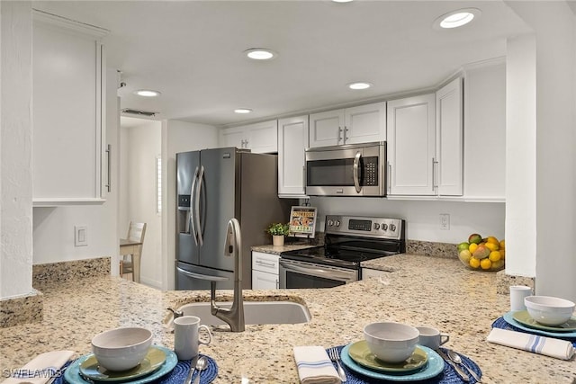 kitchen featuring white cabinets, visible vents, light stone counters, and appliances with stainless steel finishes