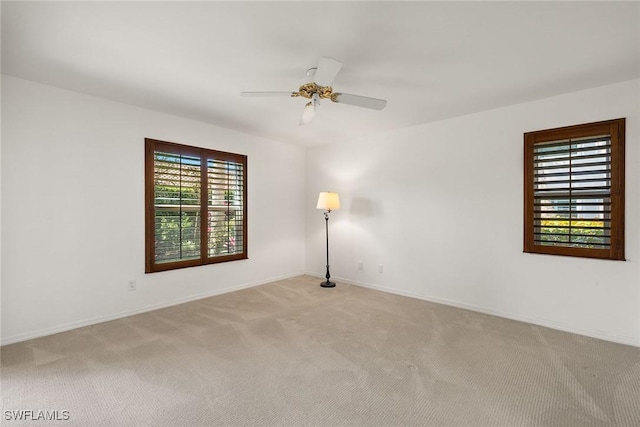 spare room with light colored carpet, baseboards, and ceiling fan