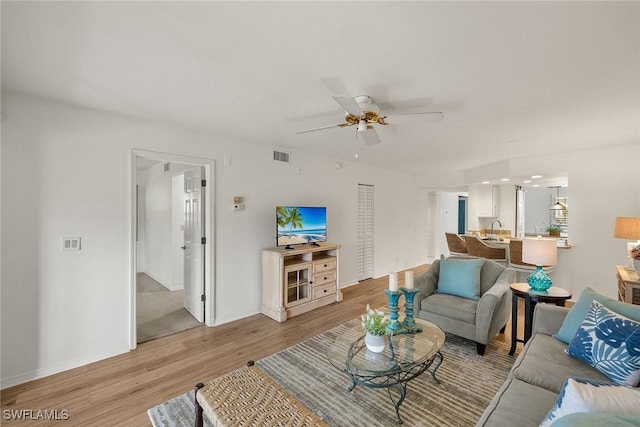 living room with light wood finished floors, baseboards, a ceiling fan, and visible vents