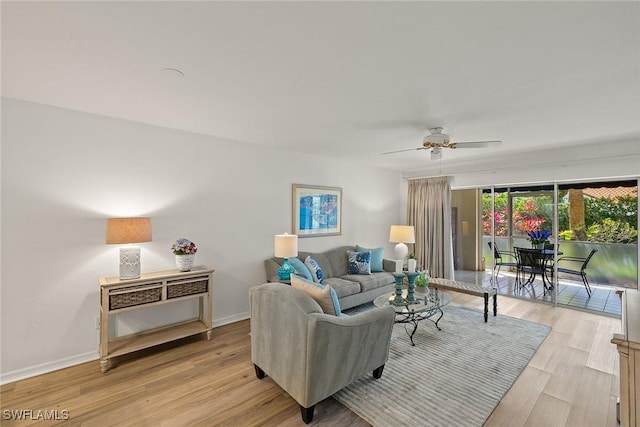 living area featuring light wood-style flooring, a ceiling fan, and baseboards