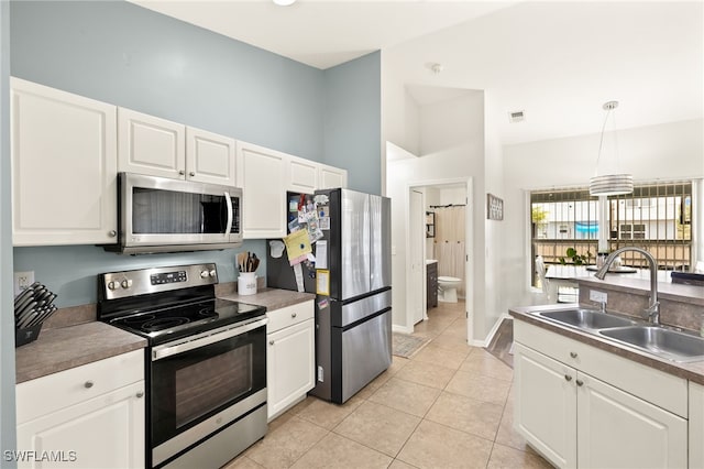 kitchen featuring white cabinetry, light tile patterned floors, stainless steel appliances, and a sink