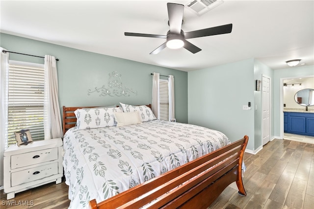 bedroom with baseboards, visible vents, wood finished floors, and ensuite bathroom
