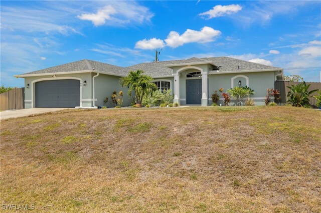 ranch-style house featuring a front lawn, fence, stucco siding, and an attached garage