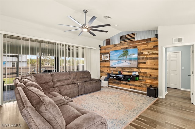 living area featuring wood walls, visible vents, ceiling fan, vaulted ceiling, and wood finished floors