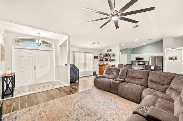living room featuring visible vents, baseboards, wood-type flooring, vaulted ceiling, and ceiling fan with notable chandelier