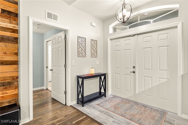 foyer featuring an inviting chandelier, visible vents, wood finished floors, and baseboards