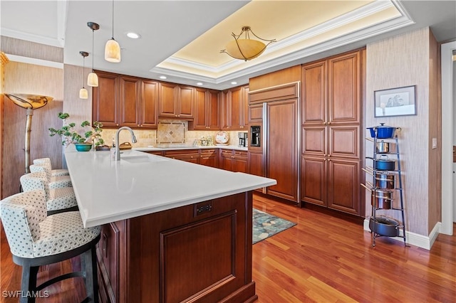 8787 Bay Colony Dr Unit 803, Naples, FL 34108 - kitchen featuring a raised ceiling, paneled refrigerator, a peninsula, a sink, and a breakfast bar area