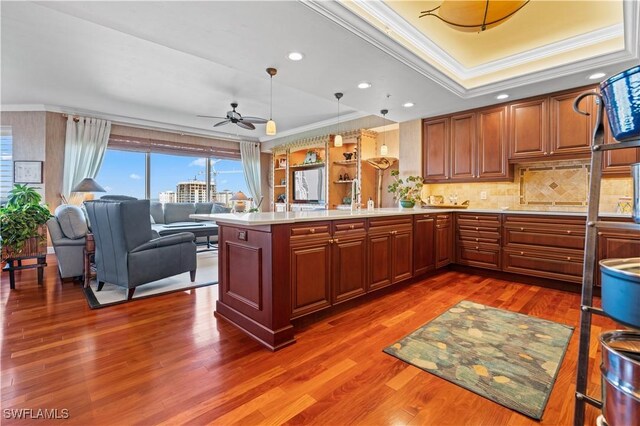 8787 Bay Colony Dr Unit 803, Naples, FL 34108 - kitchen featuring crown molding, a tray ceiling, light countertops, a peninsula, and decorative backsplash