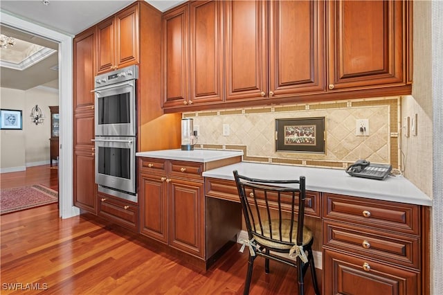 8787 Bay Colony Dr Unit 803, Naples, FL 34108 - kitchen with double oven, light countertops, wood finished floors, and tasteful backsplash