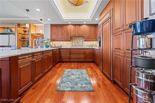 8787 Bay Colony Dr Unit 803, Naples, FL 34108 - kitchen featuring brown cabinets, a tray ceiling, light wood-type flooring, light countertops, and crown molding