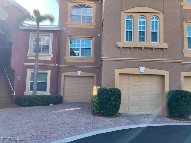 view of front of house with an attached garage, stucco siding, and driveway