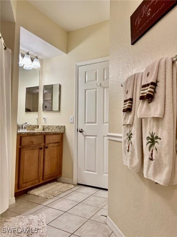 bathroom featuring baseboards, tile patterned flooring, and vanity