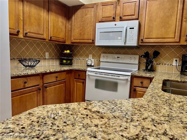 kitchen featuring decorative backsplash, brown cabinets, and white appliances