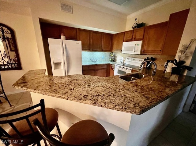 kitchen featuring a sink, stone countertops, white appliances, visible vents, and decorative backsplash