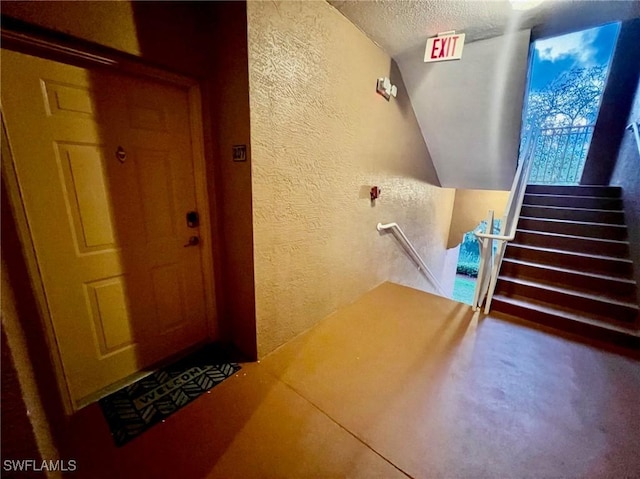 stairs with a textured ceiling and a textured wall