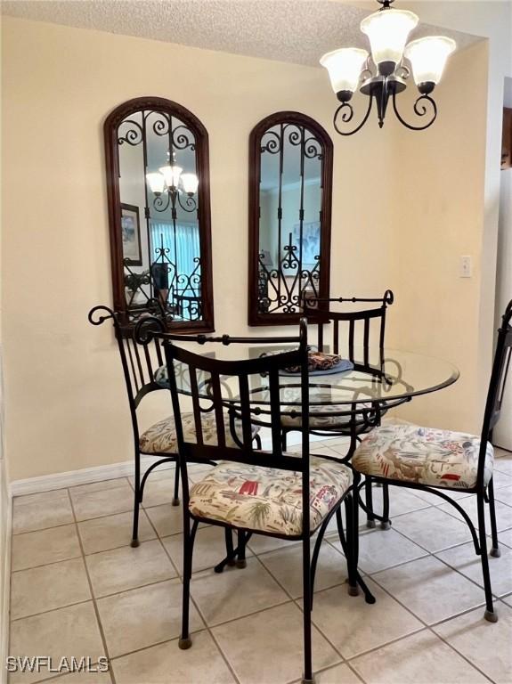 dining room with a textured ceiling, a chandelier, and light tile patterned flooring