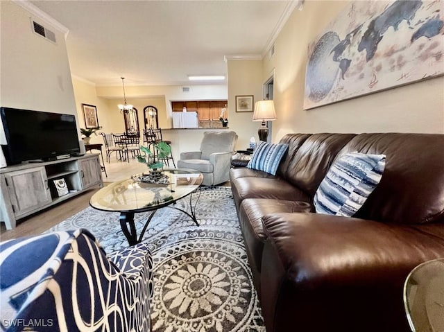 living area featuring crown molding, wood finished floors, visible vents, and a chandelier