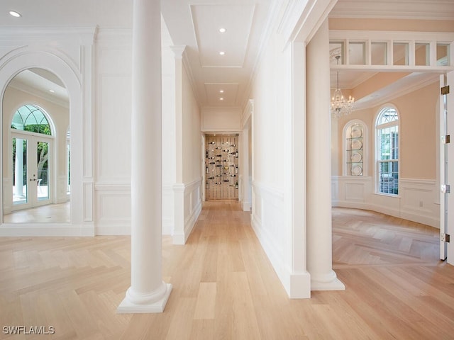 corridor featuring a decorative wall, french doors, arched walkways, and a healthy amount of sunlight