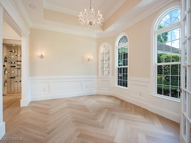 empty room featuring a raised ceiling, a chandelier, and a healthy amount of sunlight