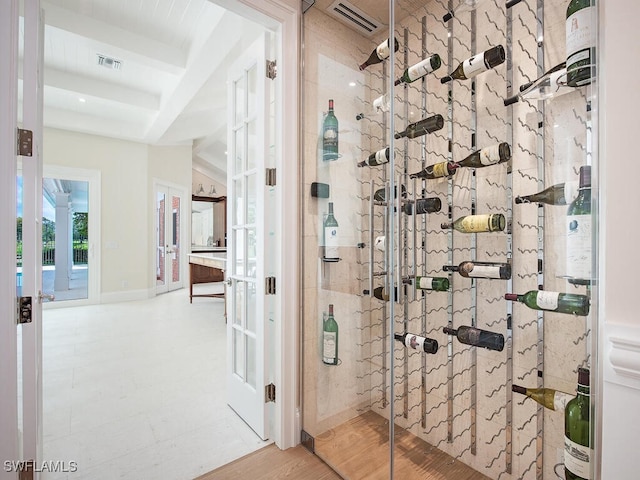 wine room featuring visible vents, beamed ceiling, and wood finished floors