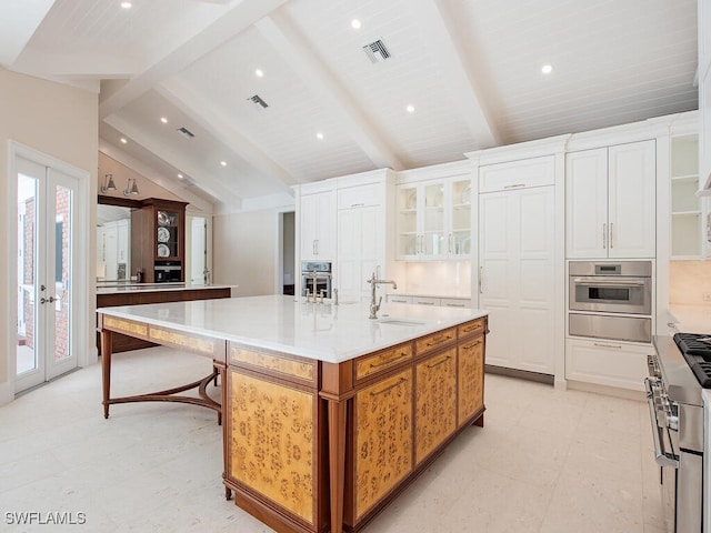 kitchen with visible vents, a sink, appliances with stainless steel finishes, a spacious island, and vaulted ceiling with beams