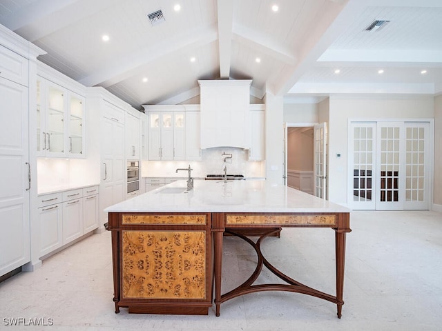 kitchen featuring visible vents, lofted ceiling with beams, a sink, light countertops, and backsplash