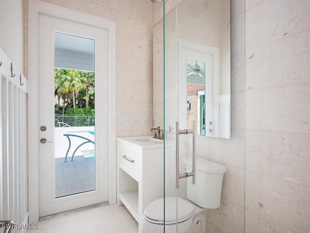 bathroom with toilet, vanity, tile patterned flooring, and tile walls