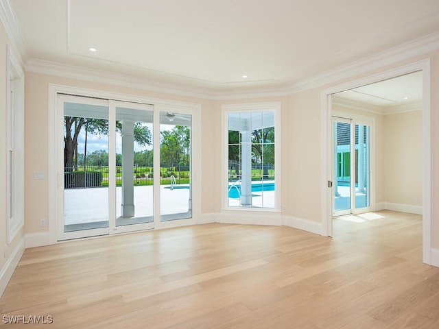 unfurnished room with light wood-type flooring, crown molding, and baseboards