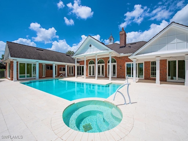 view of pool with a patio area, french doors, and a pool with connected hot tub
