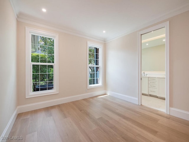 spare room with light wood-style floors, baseboards, ornamental molding, and a wealth of natural light