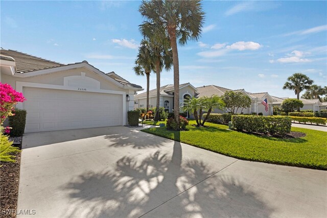 26036 Clarkston Dr, Bonita Springs, FL 34135 - view of front of house featuring a garage, driveway, a front yard, a residential view, and stucco siding