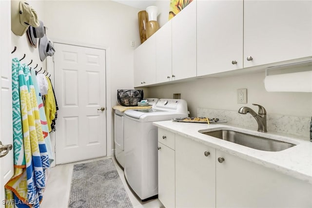washroom featuring washing machine and dryer, a sink, and cabinet space
