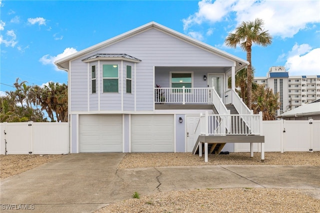 7868 Buccaneer Dr, Fort Myers Beach, FL 33931 - coastal home with covered porch, driveway, a gate, a garage, and stairs