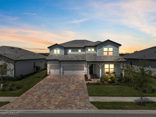 4151 Traditions Dr, Ave Maria, FL 34142 - view of front of house with board and batten siding, decorative driveway, an attached garage, a porch, and a lawn